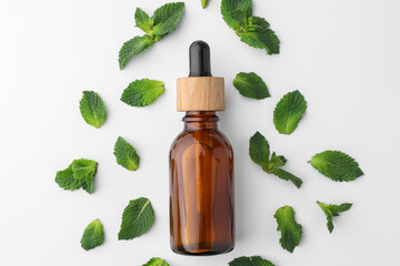 Bottle of essential oil and mint isolated on white, top view