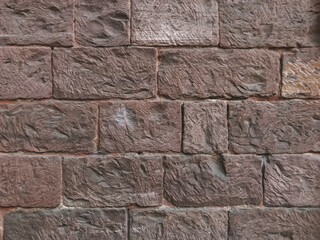 A brick wall with a rough texture and a brown color