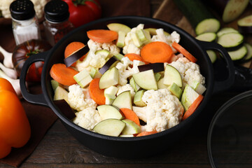 Cooking stew. Cut raw vegetables in pot on wooden table, closeup