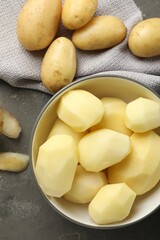 Fresh raw potatoes and peels on grey table, top view