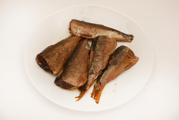 Sprats on a white plate. Canned fish in oil. Fish appetizer.