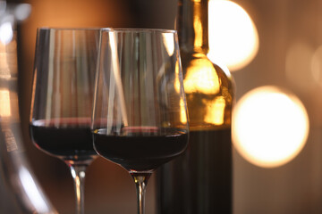 Tasty wine in glass and bottle against blurred lights, closeup