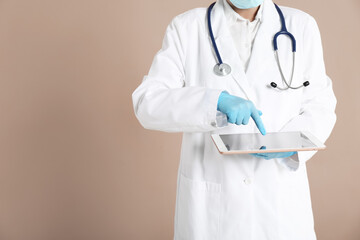 Doctor with tablet on beige background, closeup view. Space for text