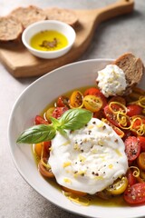 Delicious fresh burrata salad in bowl on gray table, closeup