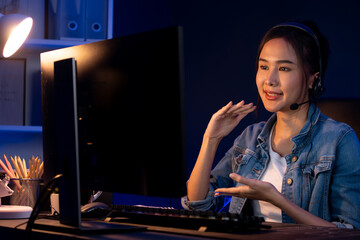 Host channel Asian influencer talking in broadcast streaming online wearing headsets on social media with pc recording, greeting listeners and coaching market online at neon modern studio. Stratagem.