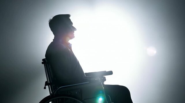 Disabled man sitting in wheelchair can't walk silhouette. Person holds his hands on wheel. Guy sit in chair. Depression concept. Man undergoing rehabilitation after accident, concept of hope.