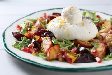 Plate with fresh burrata salad on white wooden table, closeup