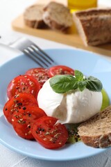 Delicious burrata cheese, tomatoes, basil and bread on white table, closeup