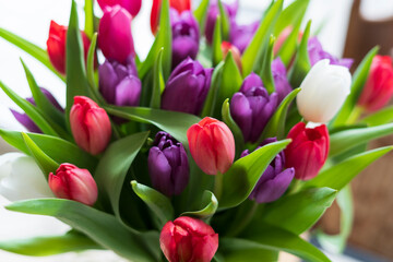 A bouquet of multi-colored tulips on the table. The concept of spring joy, celebration and freshness