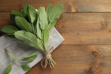 Bunch of green sage leaves on wooden table, top view. Space for text