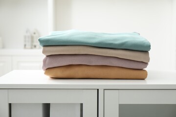 Stack of clean clothes on white dresser indoors