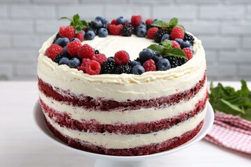 Tasty sponge cake with different berries and mint on white table