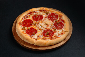Round pepperoni pizza with melted mozzarella cheese and jalapeno pepper slices on a wooden board
