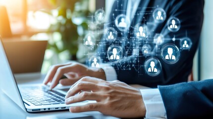 A person is typing on a laptop with a large number of people icons on the screen