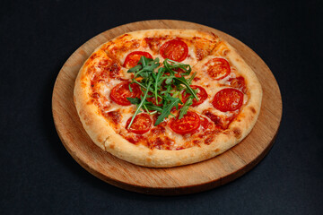 Delicious pizza margherita with arugula and tomatoes is lying on wooden plate