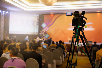 Camcorder while filming. TV camera in conference or seminar. Video camera with blur background.