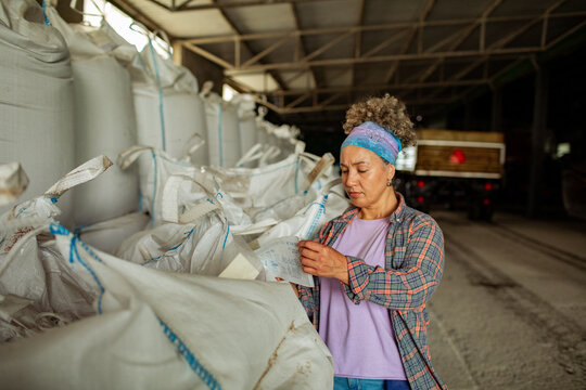 Female farmer checking inventory in warehouse with large storage bags