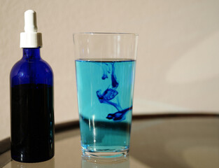image showing a bottle filled with methylene blue  near a glass with water and methylene blue.