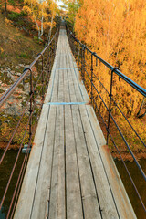 Fototapeta premium a suspension bridge over the river on an autumn day