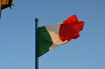 Bandera italiana: verde, blanca y roja; movida por el  viento al atardecer.