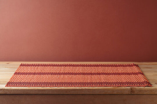 Empty wooden table with bamboo place mat over brown wall background.  Kitchen mock up for design and product display