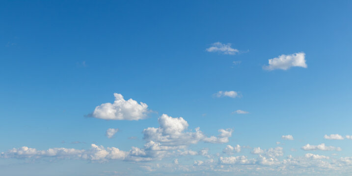Sky replacement small puffy white clouds coming in under blue sky