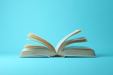 Fototapeta premium A minimalistic stock photo of an open book with pages turning, isolated against a blue background