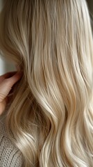 Fototapeta premium Close-up of a woman’s back showcasing soft, flowing blonde hair in a minimalist setting