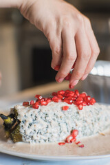 Preparation of the famous chiles en Nogada, traditional Mexican food in the month of September, stuffed chile being covered by the nogada which is a cream with walnut and hand adding pomegranate.