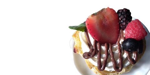 Cream puff with chocolate syrup and fruit topping on white plate isolated.