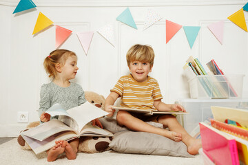 Children enjoy story time while sit in decorated room with books