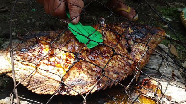 Grilling gourami fish over open flames, with crispy skin and smoky flavor, ideal for food content