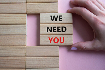 We need you symbol. Concept words We need you on wooden blocks. Beautiful pink background. Businessman hand. Business and We need you concept. Copy space.