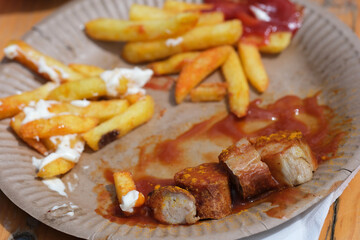 Verschwendung von Lebensmitteln, Currywurst- und Pommesreste auf einem Pappteller