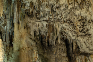 Stalactites and stalagmites in a cave illuminated by multi-colored light