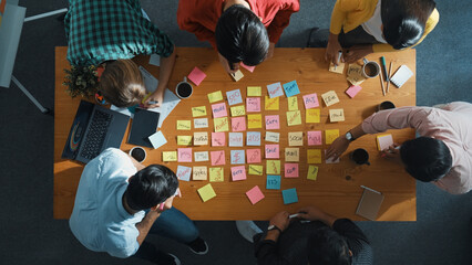 Top down view of smart diverse business people writing marketing idea at meeting and brainstorming...