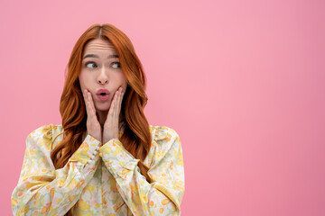 Long-haired pretty ginger woman looking astonished and looking aside