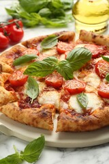 Delicious Margherita pizza and ingredients on white marble table, closeup