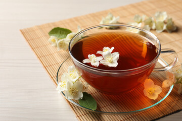 Hot jasmine tea in cup and flowers on white wooden table
