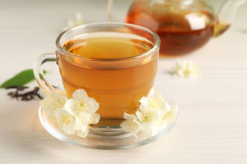 Hot jasmine tea in cup and flowers on white wooden table