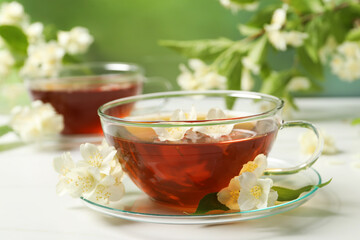 Hot jasmine tea in cup and flowers on white marble table