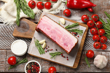 Piece of raw bacon with spices and cherry tomatoes on wooden table, flat lay