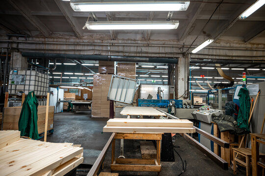 modern woodworking factory interior showing stacks of wooden boards and workers in the background, organized for efficient production and storage