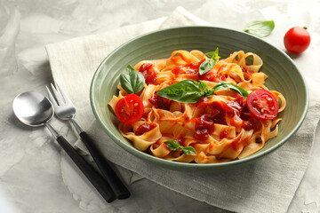 Delicious pasta with tomato sauce and basil served on grey textured table, closeup