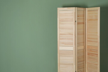 Wooden folding screen near green wall indoors, space for text