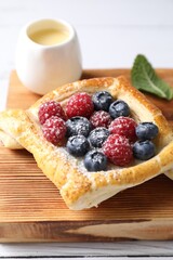 Tasty puff pastry with berries on white wooden table, closeup