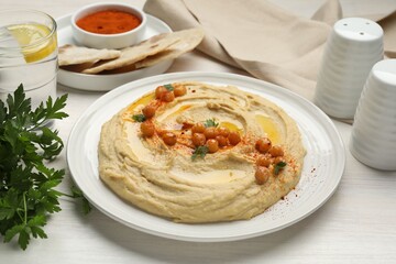 Delicious hummus with olive oil, chickpeas and paprika served on white wooden table