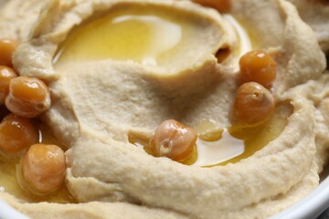 Delicious hummus with olive oil and chickpeas in bowl, closeup