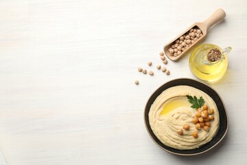 Delicious hummus with olive oil, chickpeas and parsley on white wooden table, flat lay. Space for text