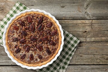 Delicious pecan pie in baking dish on wooden table, top view. Space for text